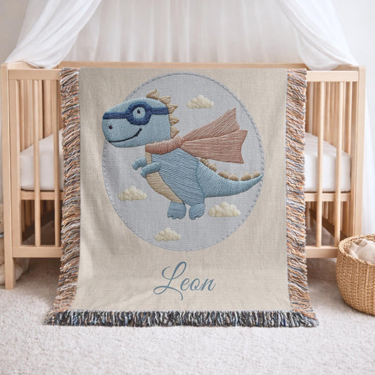 Personalized dinosaur woven baby blanket in 100% cotton. Embroidered-look superhero dino design, custom name keepsake for nursery decor.