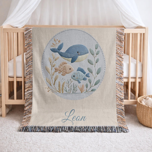This personalized woven baby blanket features a gentle ocean theme with a sweet whale and fish design in a soft embroidered-look style.