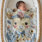 Embroidered-look giraffe blanket with floral crown and soft blue–peach details. Cozy fabric, gentle colors — a sweet newborn gift and neutral nursery decor.