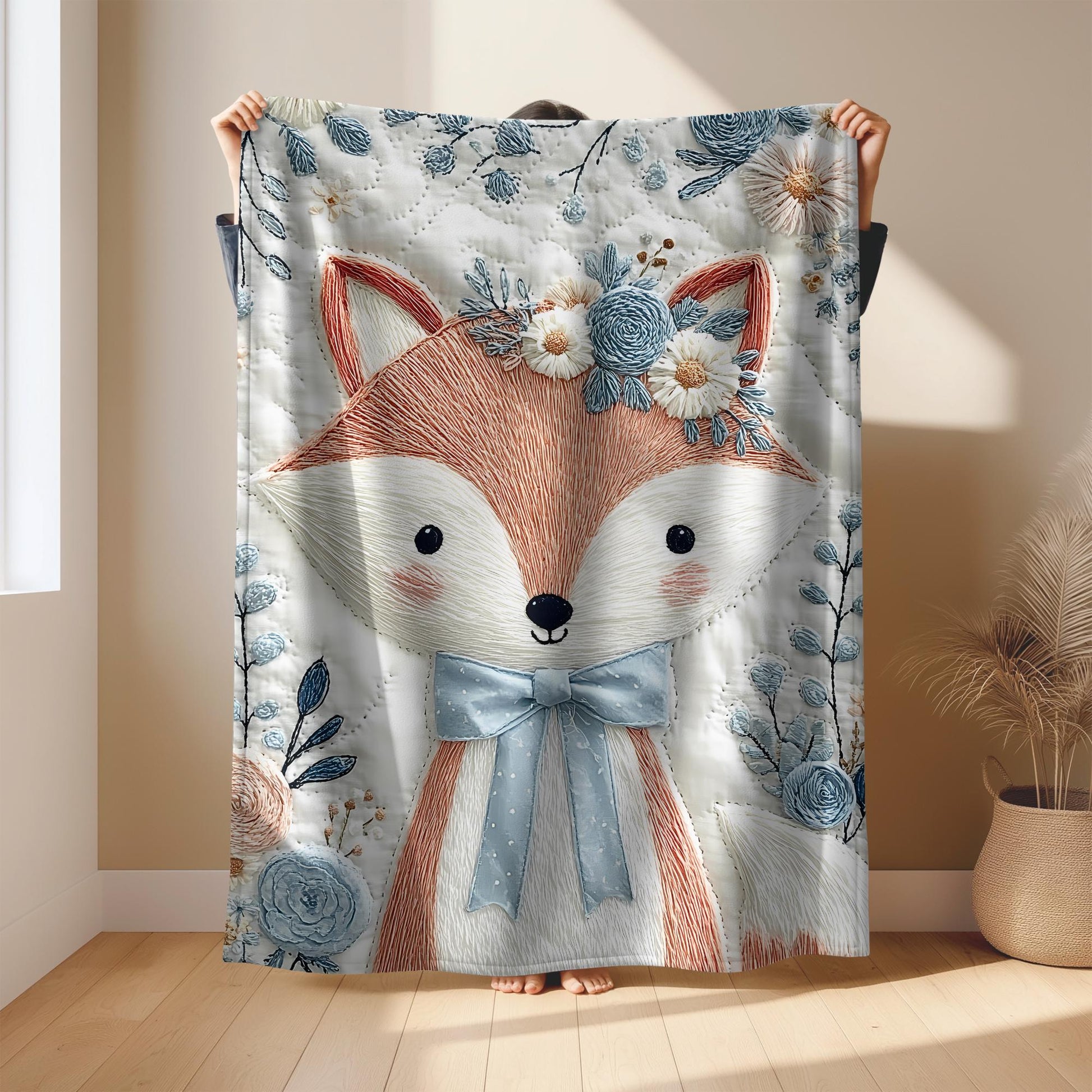 Embroidered-look fox baby blanket with soft floral crown and gentle blue–peach stitched details on a neutral background.