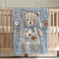 Embroidered-look teddy bear girl baby blanket with floral details on a soft blue quilted background.