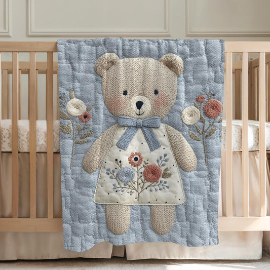 Embroidered-look teddy bear girl baby blanket with floral details on a soft blue quilted background.