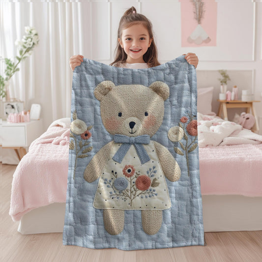 Embroidered-look teddy bear girl baby blanket with floral details on a soft blue quilted background.