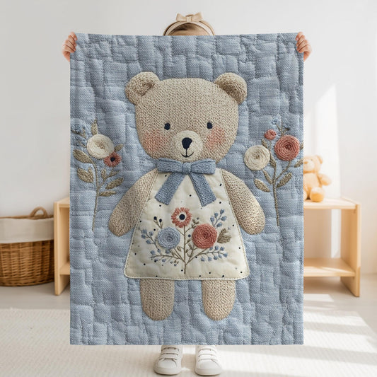 Embroidered-look teddy bear girl baby blanket with floral details on a soft blue quilted background.