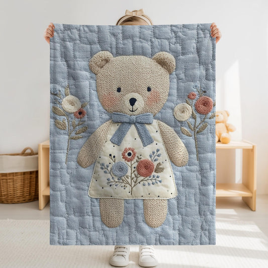 Embroidered-look teddy bear girl baby blanket with floral details on a soft blue quilted background.