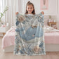 This embroidered look baby blanket features a gentle whale with a delicate bow, surrounded by soft floral elements in calming blue, cream, and natural tones.