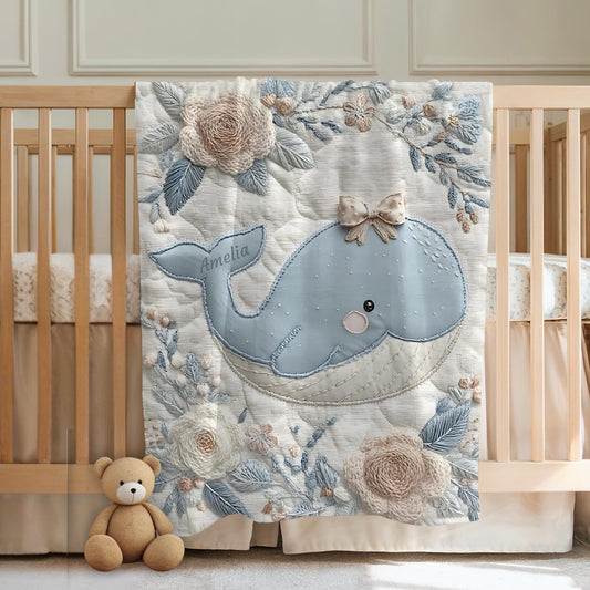 This embroidered look baby blanket features a gentle whale with a delicate bow, surrounded by soft floral elements in calming blue, cream, and natural tones.