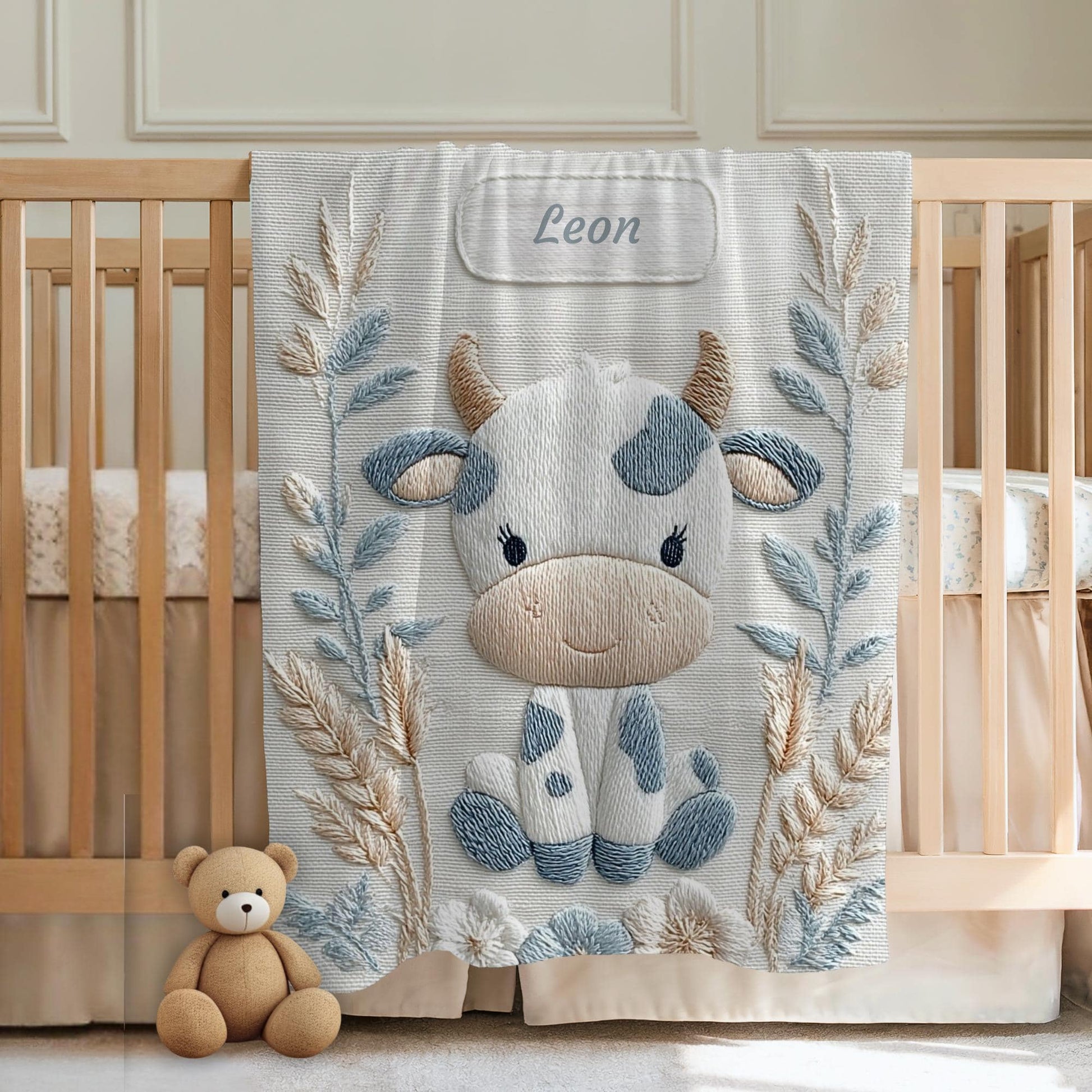 Cow embroidered-look baby blanket with pastel florals. Neutral tones, cozy fabric — a boutique newborn gift for calm, modern nursery decor.