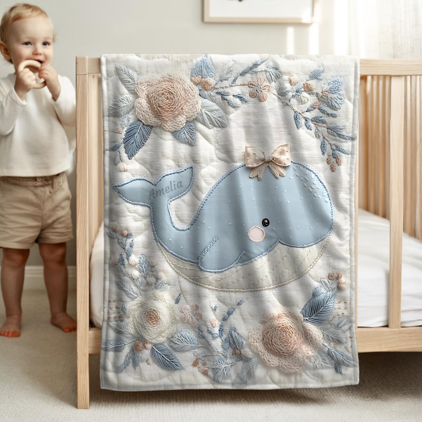 This embroidered look baby blanket features a gentle whale with a delicate bow, surrounded by soft floral elements in calming blue, cream, and natural tones.
