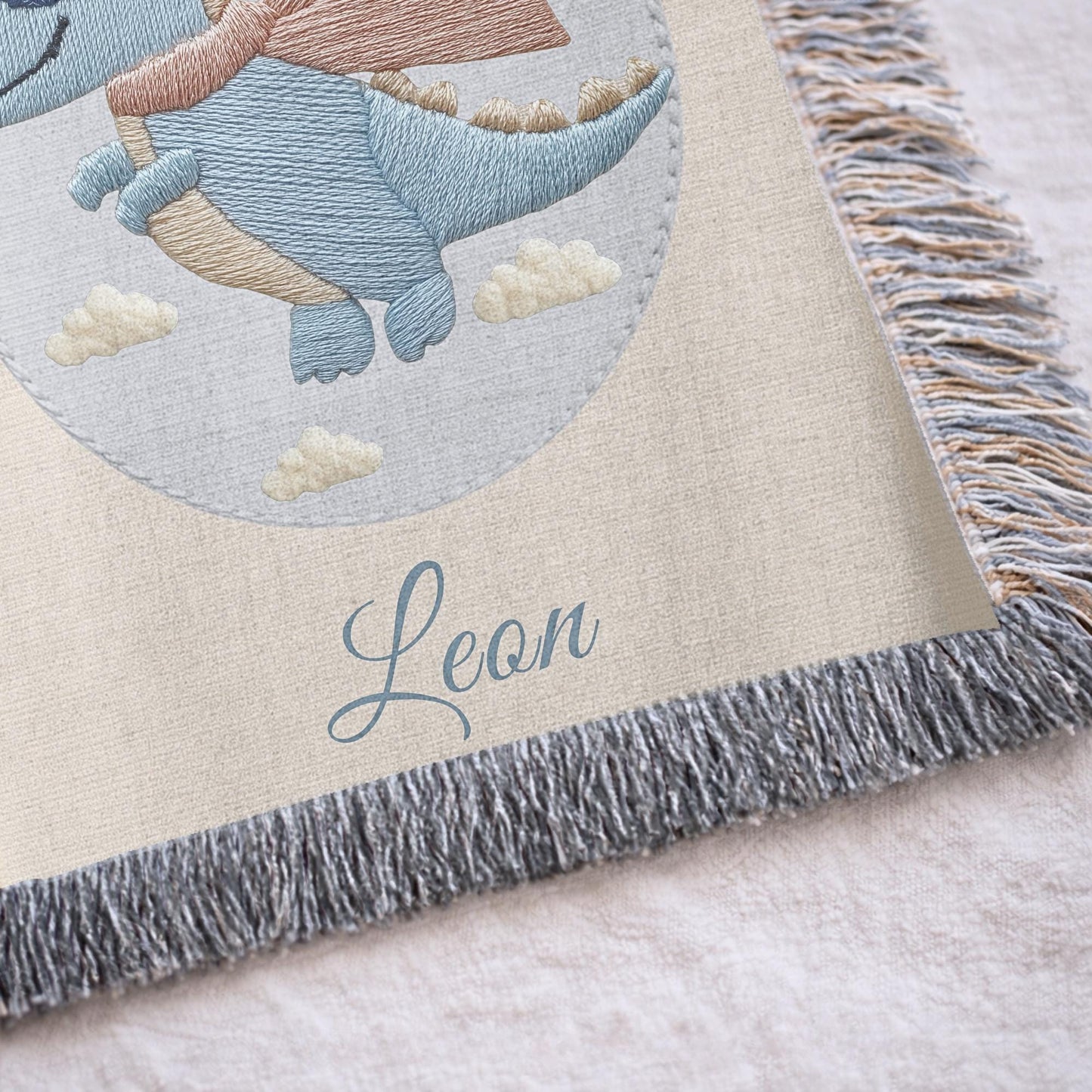 Personalized dinosaur woven baby blanket in 100% cotton. Embroidered-look superhero dino design, custom name keepsake for nursery decor.