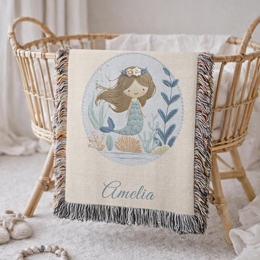 Personalized woven baby blanket featuring a calm mermaid design. Ocean under the sea nursery decor, crafted as a soft cotton tapestry keepsake.
