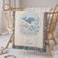 This personalized woven baby blanket features a gentle ocean theme with a sweet whale and fish design in a soft embroidered-look style.