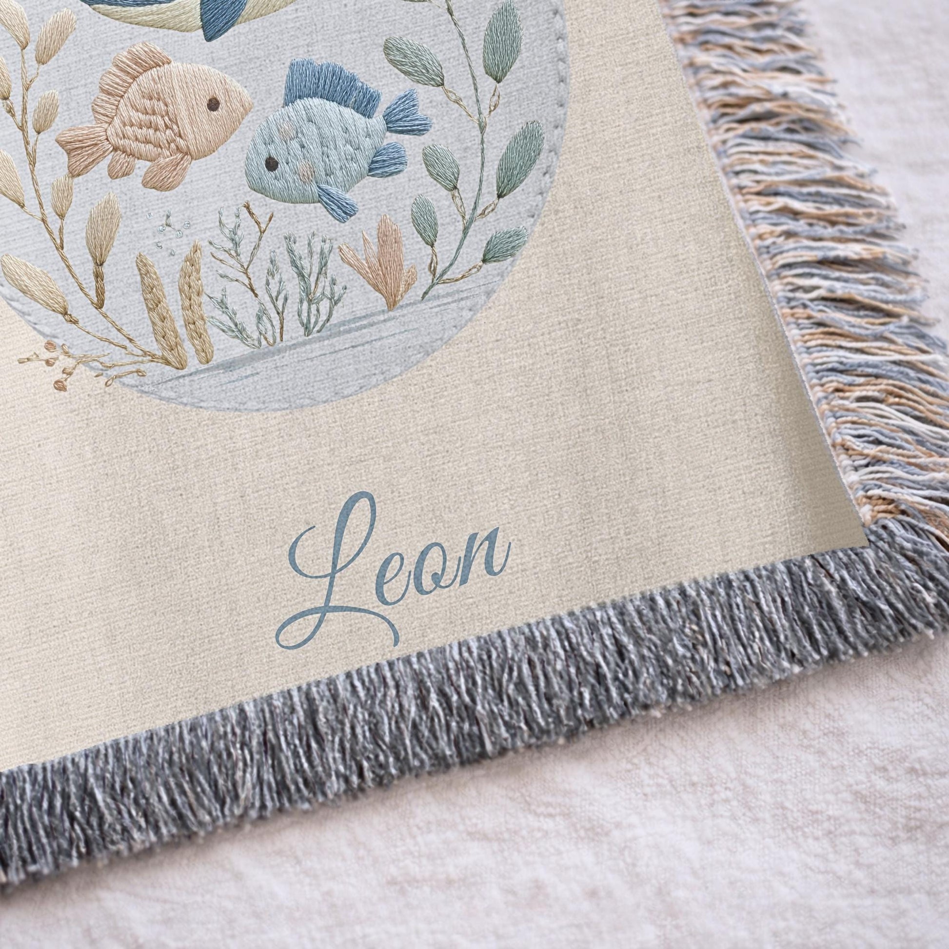 This personalized woven baby blanket features a gentle ocean theme with a sweet whale and fish design in a soft embroidered-look style.