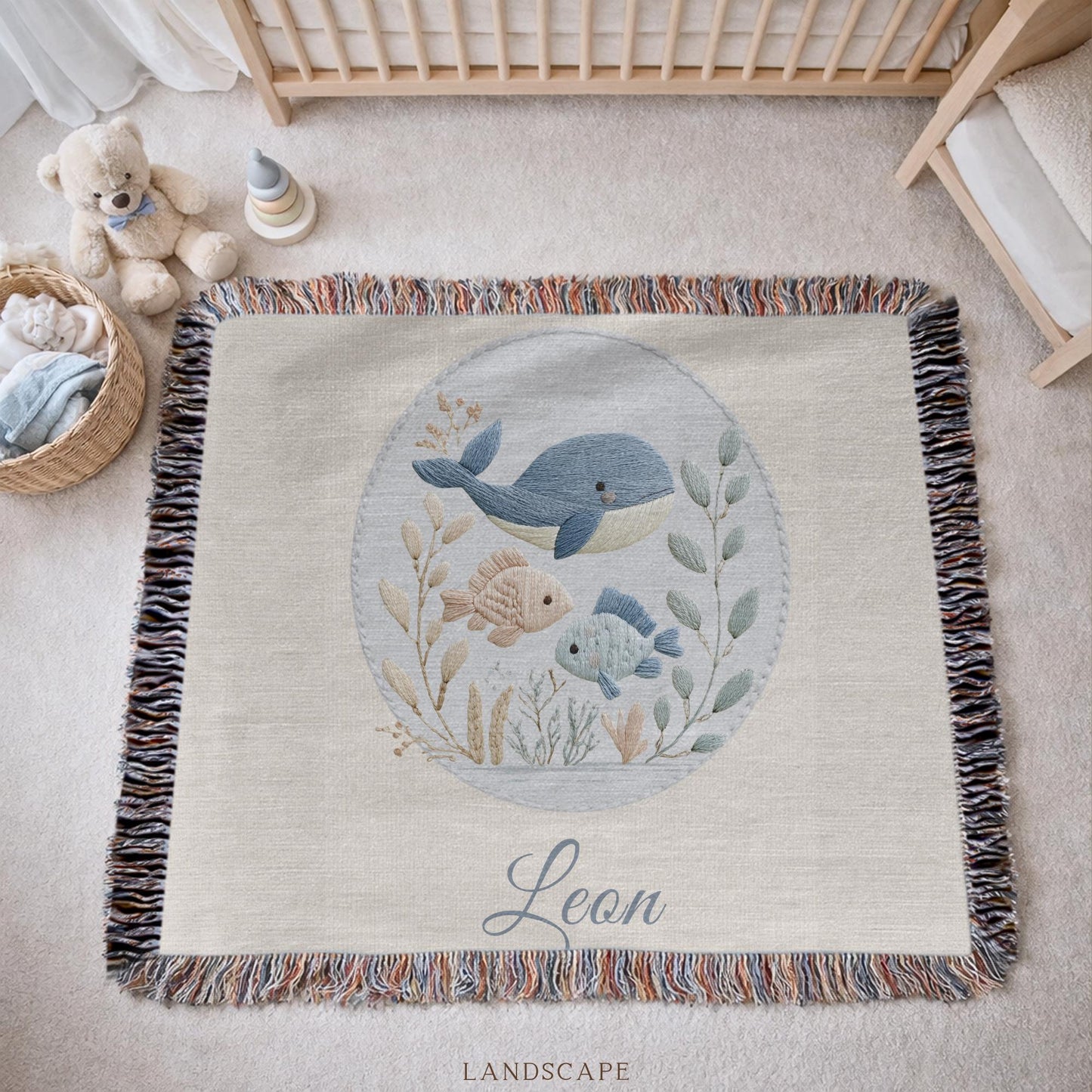 This personalized woven baby blanket features a gentle ocean theme with a sweet whale and fish design in a soft embroidered-look style.