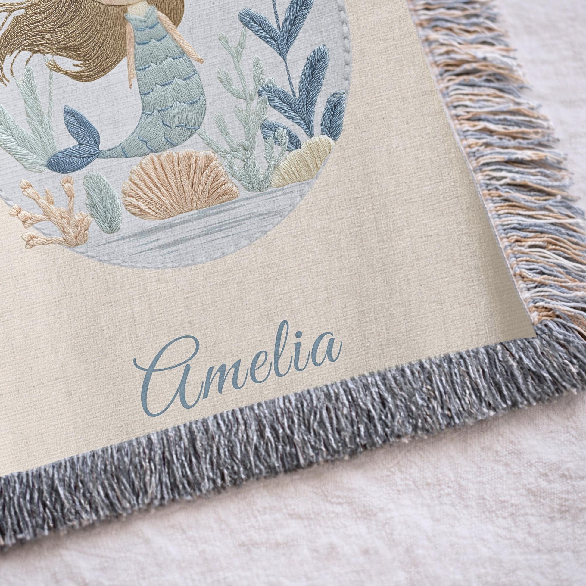 Personalized woven baby blanket featuring a calm mermaid design. Ocean under the sea nursery decor, crafted as a soft cotton tapestry keepsake.