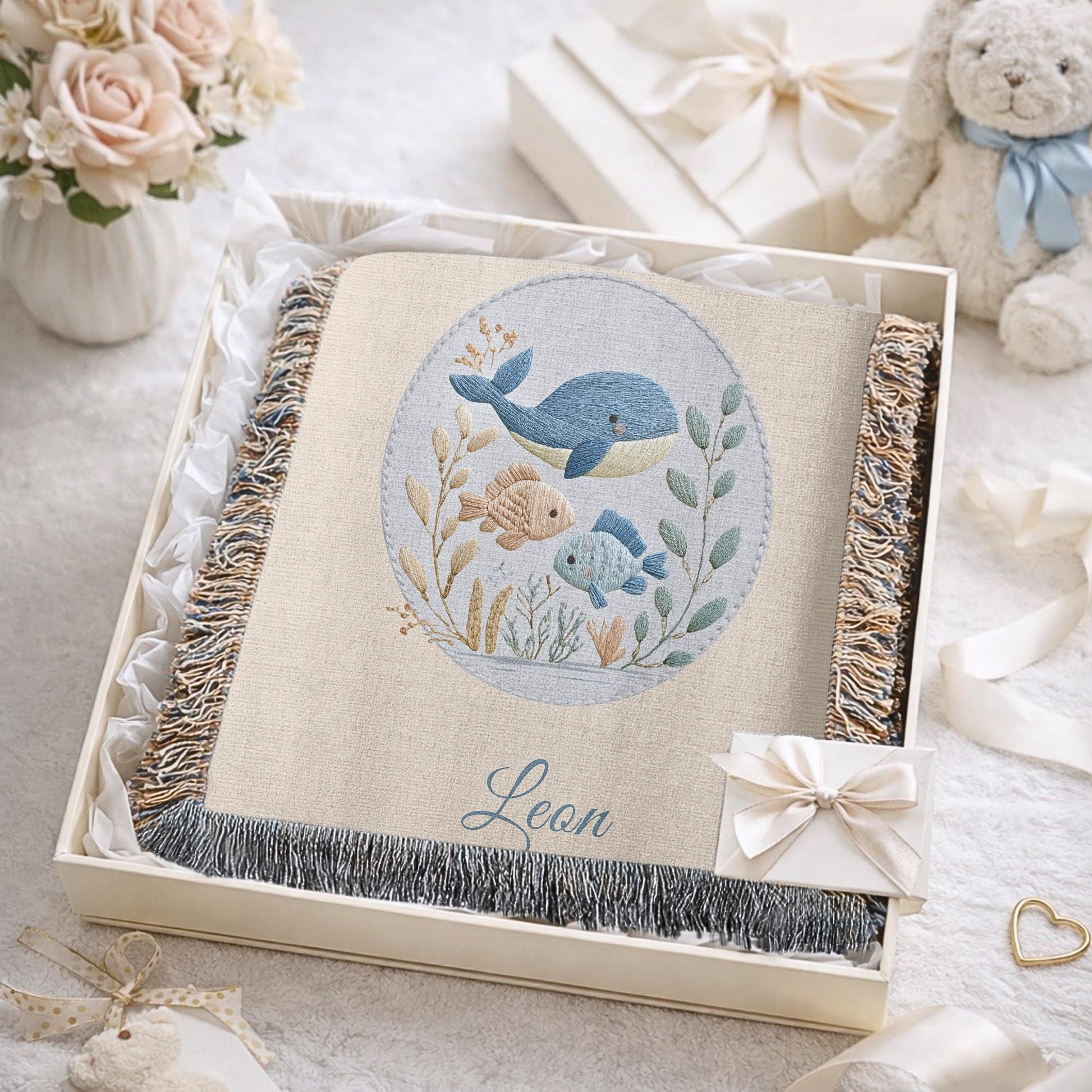 This personalized woven baby blanket features a gentle ocean theme with a sweet whale and fish design in a soft embroidered-look style.