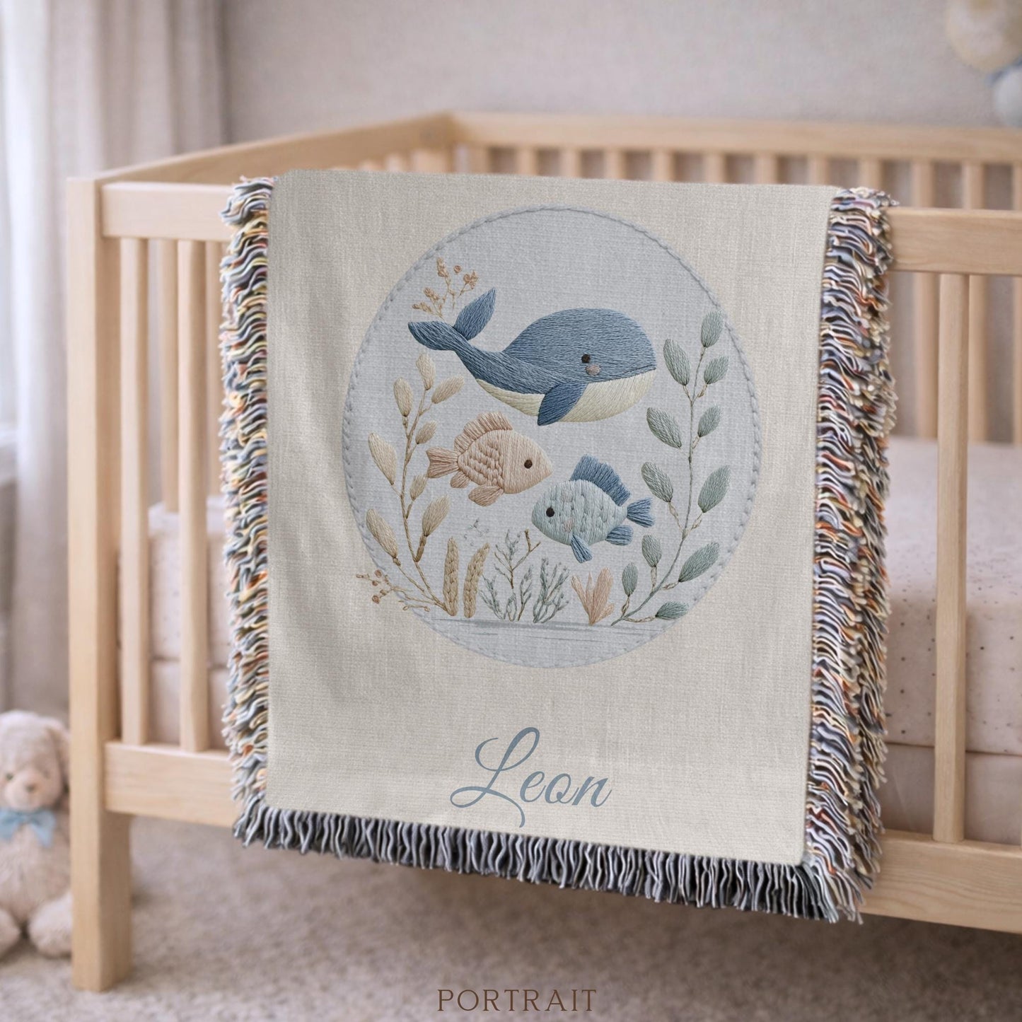 This personalized woven baby blanket features a gentle ocean theme with a sweet whale and fish design in a soft embroidered-look style.