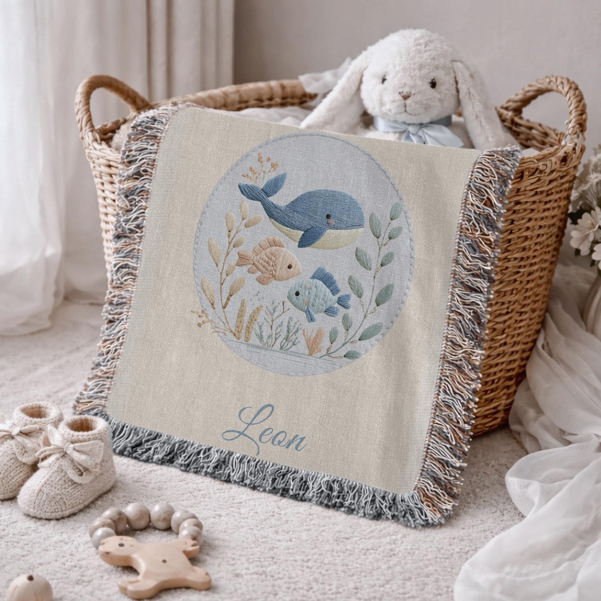 This personalized woven baby blanket features a gentle ocean theme with a sweet whale and fish design in a soft embroidered-look style.