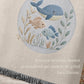 This personalized woven baby blanket features a gentle ocean theme with a sweet whale and fish design in a soft embroidered-look style.