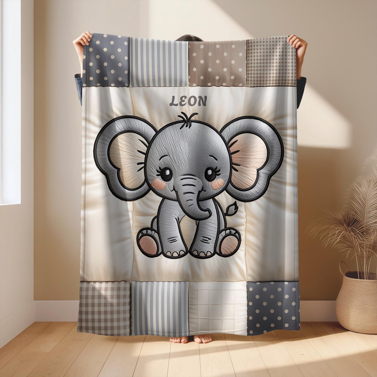 A personalized baby quilt blanket featuring a sweet elephant in an embroidered-look patchwork design. Soft neutral tones, perfect for nursery decor or a newborn gift.