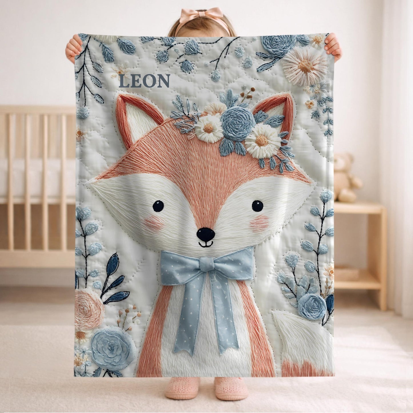 Embroidered-look fox baby blanket with soft floral crown and gentle blue–peach stitched details on a neutral background.