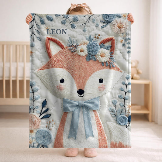 Embroidered-look fox baby blanket with soft floral crown and gentle blue–peach stitched details on a neutral background.