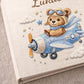 Personalized teddy bear airplane baby memory book with name and birth date. A soft aviation nursery album for first memories and milestones.