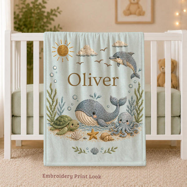 Personalized Ocean Baby Blanket with an embroidered-look print featuring a whale, dolphin, sea turtle, octopus, and coastal details.