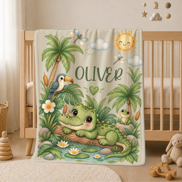 Personalized Crocodile Baby Blanket featuring an adorable little crocodile relaxing beside a tropical pond surrounded by palm trees, lush greenery, water lilies, a toucan, frog, dragonflies and a smiling sunshine. Customized with your baby’s name, this sweet jungle-inspired blanket makes a charming addition to a baby boy nursery and a meaningful keepsake for a new arrival.