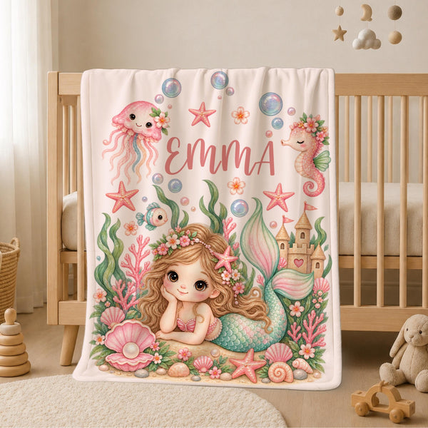 Personalized Mermaid Baby Blanket featuring a sweet little mermaid surrounded by seashells, starfish, coral, bubbles, flowers, a seahorse, jellyfish and a magical sandcastle. Customized with your baby’s name, this dreamy underwater blanket makes a beautiful addition to a baby girl nursery and a special keepsake for a precious new arrival.